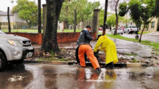 Calle de Corrientes con charco de agua tras las lluvias, con vehículos transitando.